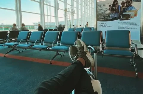 Viajante descansando com as pernas estendidas em assentos de aeroporto