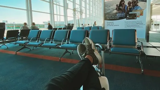Viajante descansando com as pernas estendidas em assentos de aeroporto