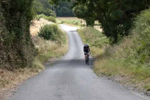 Ciclista subindo uma estrada rural