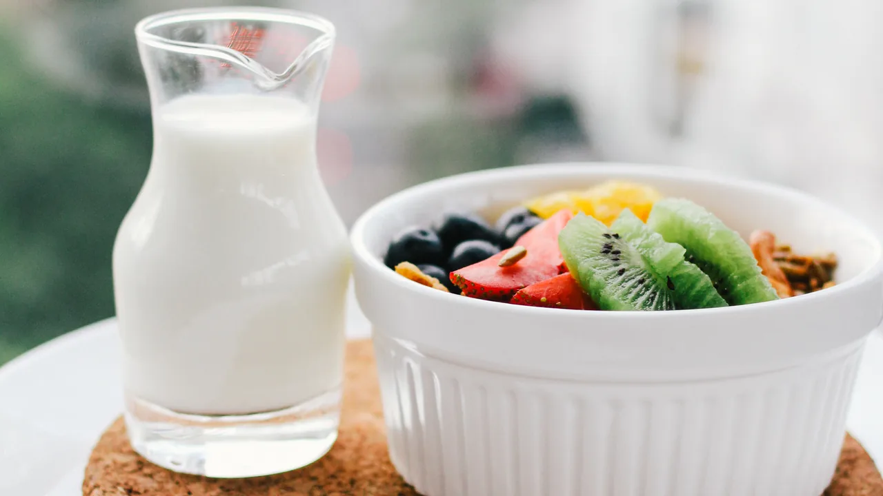 Tigela de frutas e cereal ao lado de uma jarra de leite