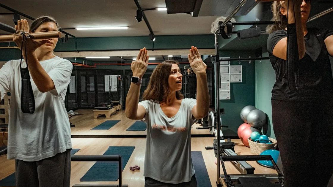 Instrutora orienta participantes durante uma aula de Pilates em estúdio
