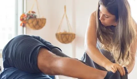 Instrutor orienta a prática de Pilates com apoio durante um exercício