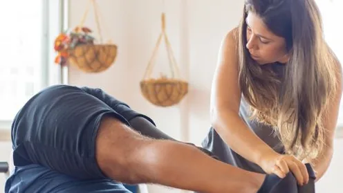 Instrutor orienta a prática de Pilates com apoio durante um exercício