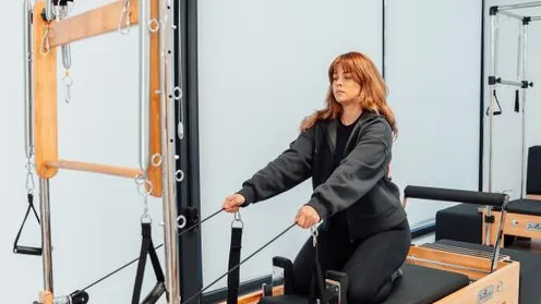 Aluna praticando Pilates individualmente em aparelho