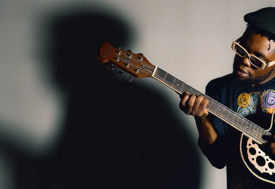 Músico tocando violão em pé, com o instrumento apoiado no corpo