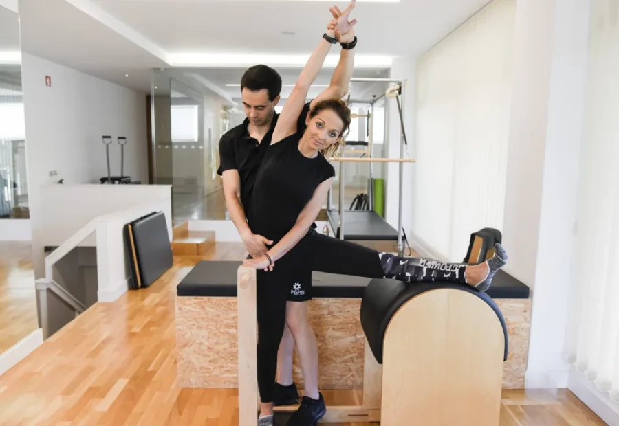 Instrutor orienta aluna em exercício de Pilates em um estúdio