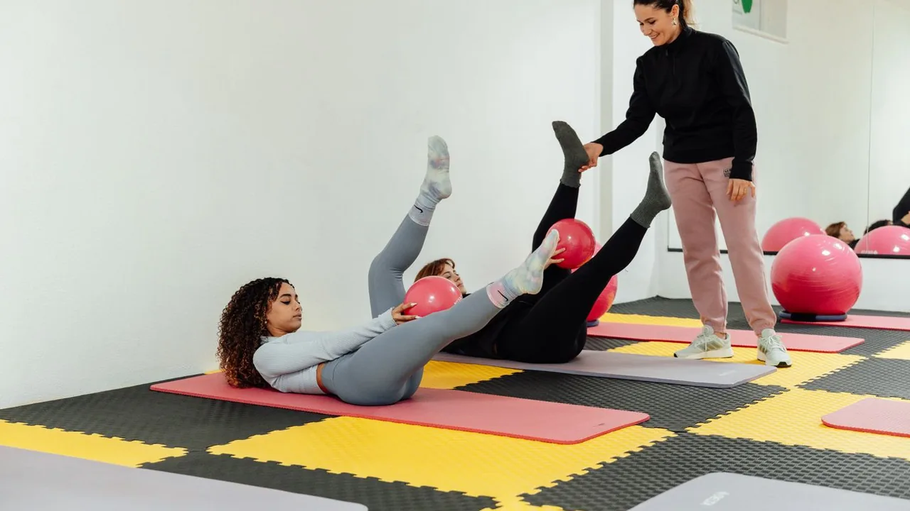 Aula coletiva de Pilates em colchonetes, com instrutora acompanhando participantes.