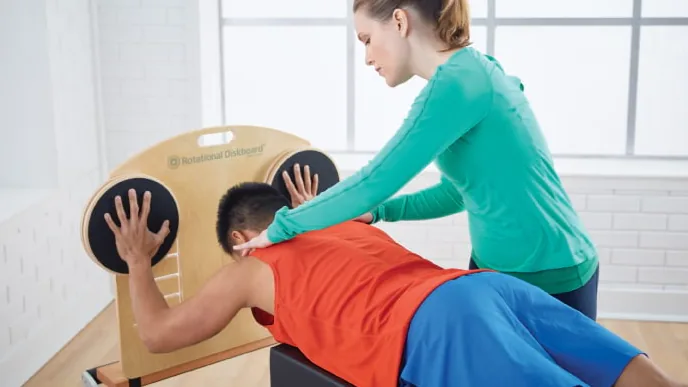 Pessoa usando Rotational Diskboard em um Reformer com orientação profissional